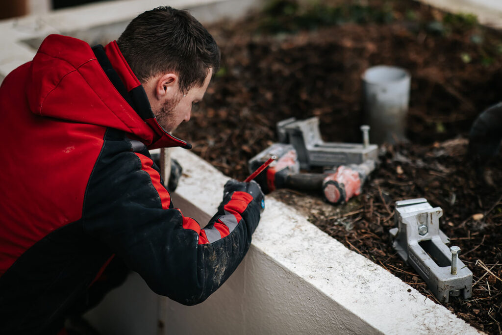 PHOTO D'UN PROFESSIONNEL DU SCIAGE BÉTON ENTRAIN DE TRACER DES MESURES SUR UN MURET BÉTON