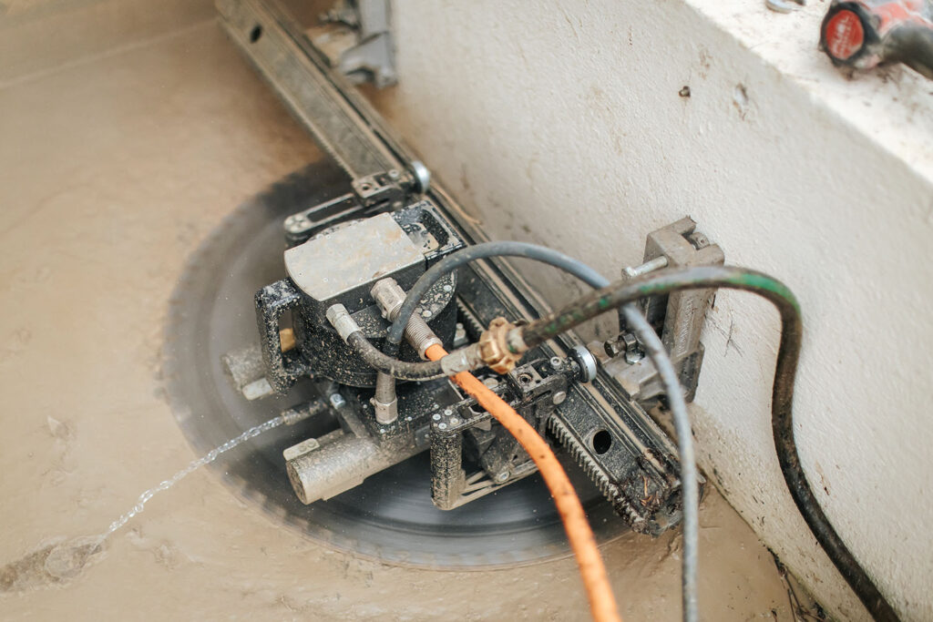 PHOTO D'UNE SCIE CIRCULAIRE ENTRAIN DE SCIER UN MURET EN BÉTON